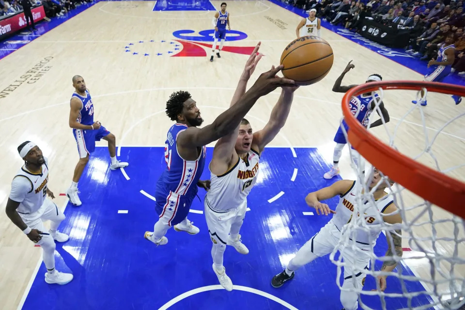 Denver Nuggets' Nikola Jokic, right, and Philadelphia 76ers' Joel Embiid reach for a rebound during the first half of an NBA basketball game, Tuesday, Jan. 16, 2024, in Philadelphia. (AP Photo/Matt Slocum)