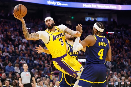 Lakers star Anthony Davis looks to take an off-balance shot as the Golden State Warriors’ Steph Curry, center, and Moses Moody defend during the first half on Thursday night in San Francisco. Davis had 27 points and 15 rebounds, but the LeBron James-less Lakers lost, 128-110. (Photo by Lachlan Cunningham/Getty Images)
