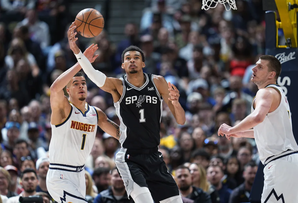 San Antonio Spurs center Victor Wembanyama, center, pulls in a rebound between Denver Nuggets forward Michael Porter Jr., left, and center Nikola Jokic during the first half of an NBA basketball game Tuesday, April 2, 2024, in Denver. (AP Photo/David Zalubowski)