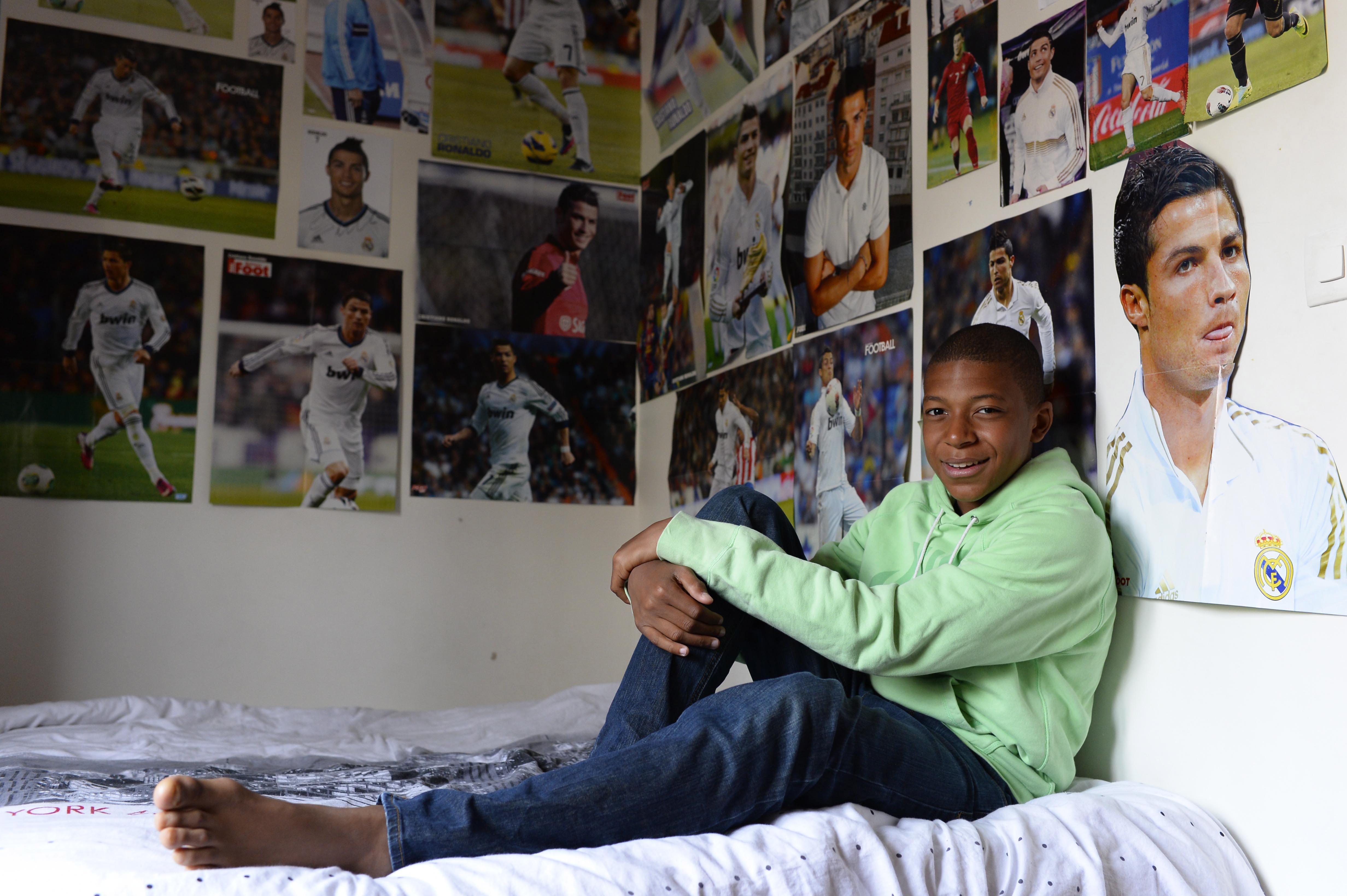 A young Mbappe poses with his posters of hero Ronaldo