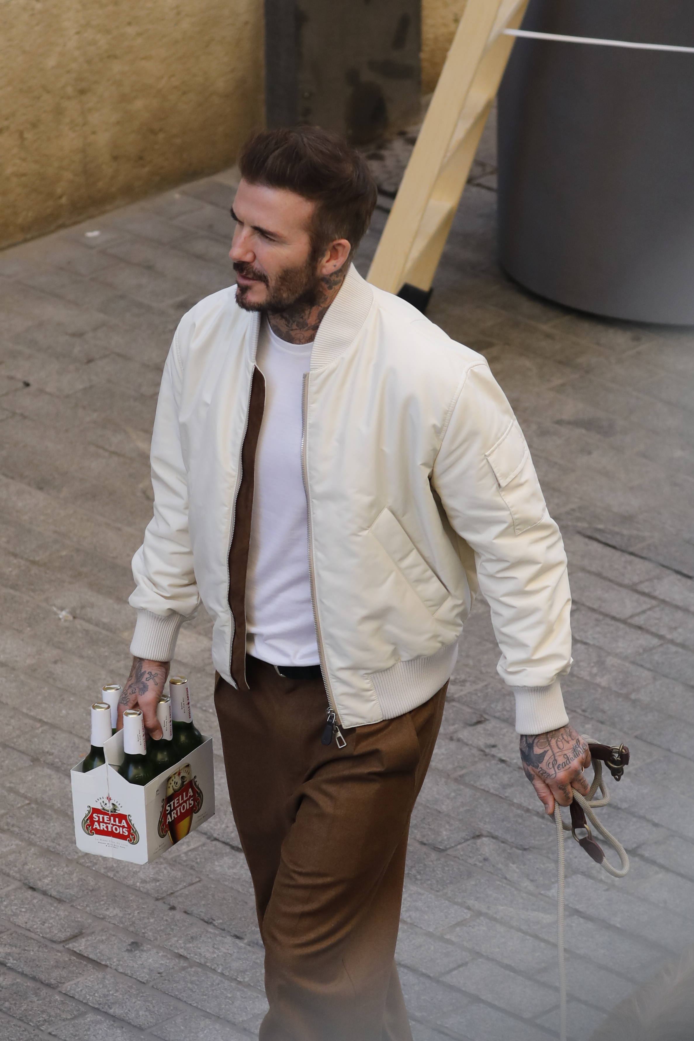 Becks, 48, looked suave in a cream bomber jacket and chocolate-brown trousers