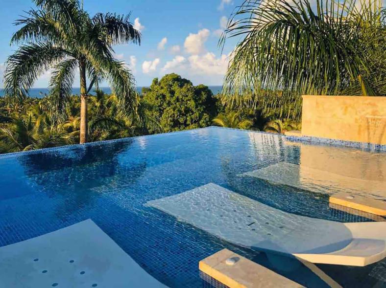 An infinity pool on the roof has fountains and built-in lounge chairs floating in the water.