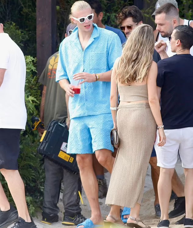 Haaland interacts with a male fan while walking on the street. The nearly 2m tall boy looks even more outstanding when covered in blue plants.